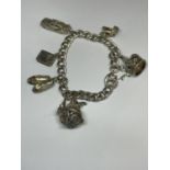 A HEAVY SILVER CHARM BRACELET WITH SIX CHARMS TO INCLUDE A CROWN, CAR, CHURCH, SLIPPERS ETC