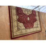 A LARGE RED AND CREAM PATTERNED RUG