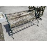 A WOODEN SLATTED GARDEN BENCH WITH DECORATIVE CAST ENDS