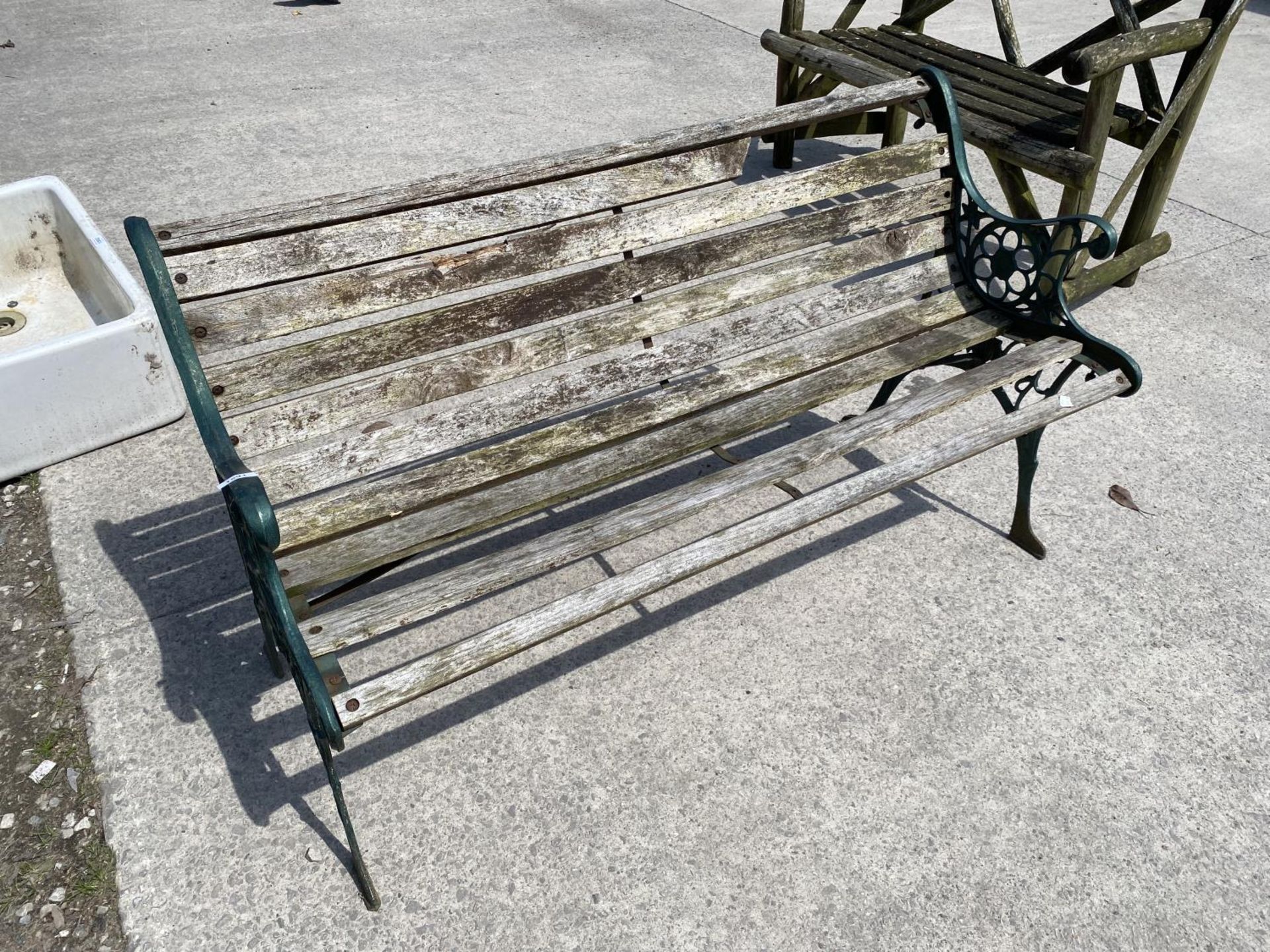 A WOODEN SLATTED GARDEN BENCH WITH DECORATIVE CAST ENDS