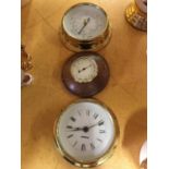 A BRASS ROUND BAROMETER, ROUND BRASS CLOCK AND A SMALLER ROUND WOODEN BAROMETER