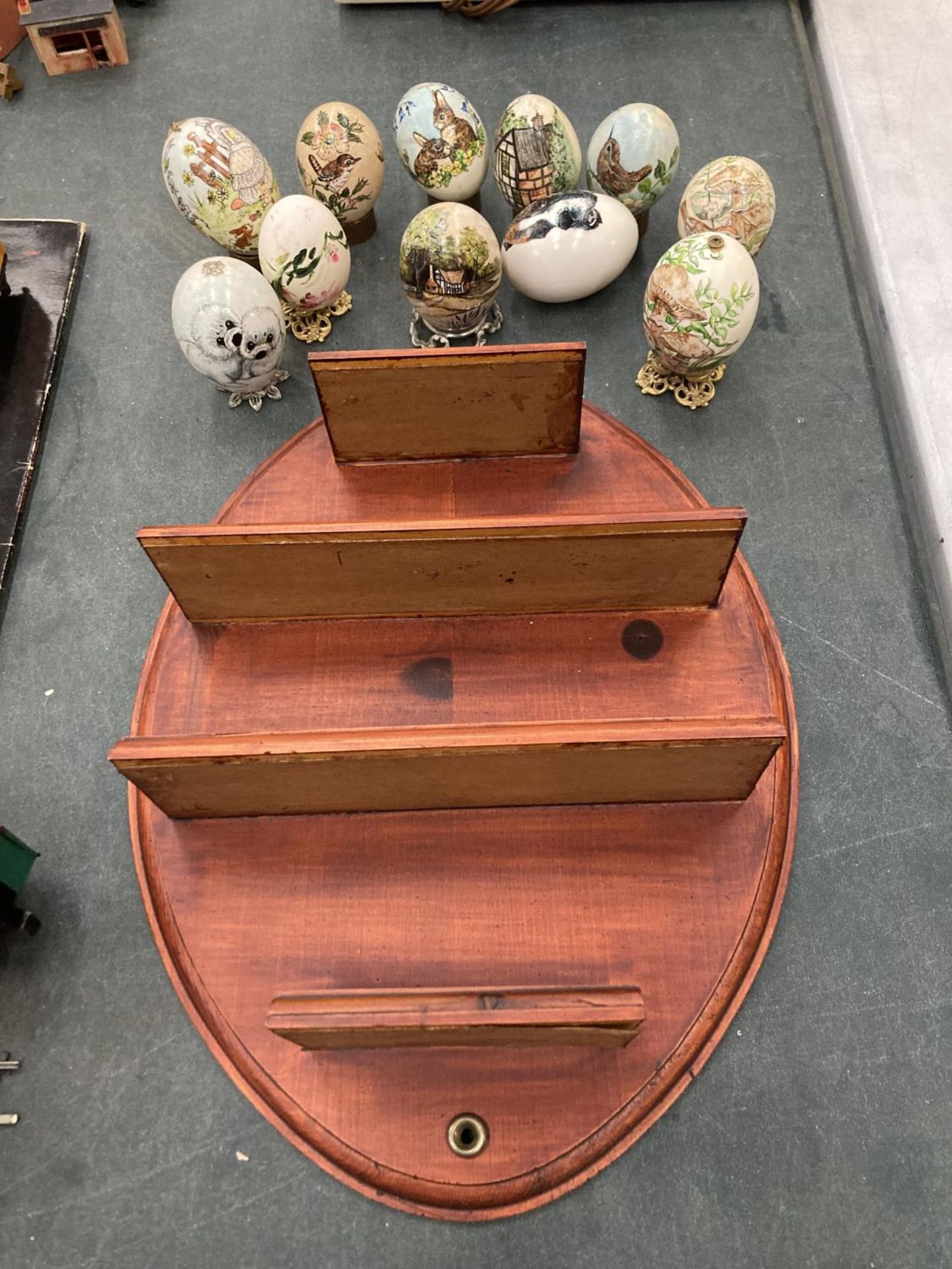 A WOODEN DISPLAY SHELF WITH A QUANTITY OF PAINTED EGGS