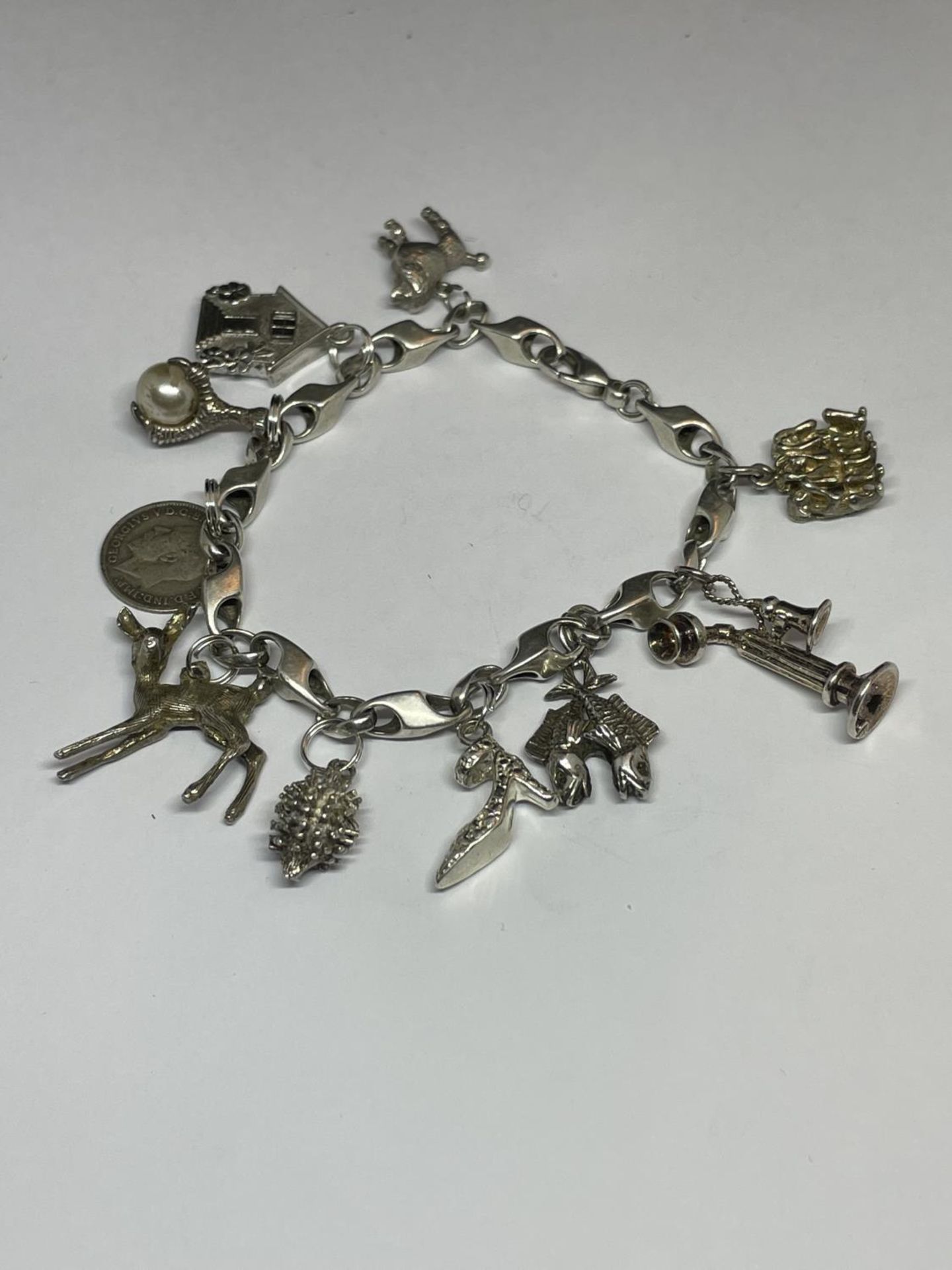 A MARKED SILVER CHARM BRACELET WITH TEN CHARMS TO INCLUDE A HEDGEHOG, SHOE, DOG, TELEPHONE ETC