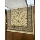 A LARGE BEIGE AND BLUE FLORAL PATTERN FRINGED RUG