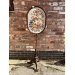 A TAPESTRY SCREEN ON A POLE WITH CARVED TRIPOD LEGS