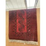 A RED AND BLACK FRINGED PATTERN RUG 105CM X 195CM