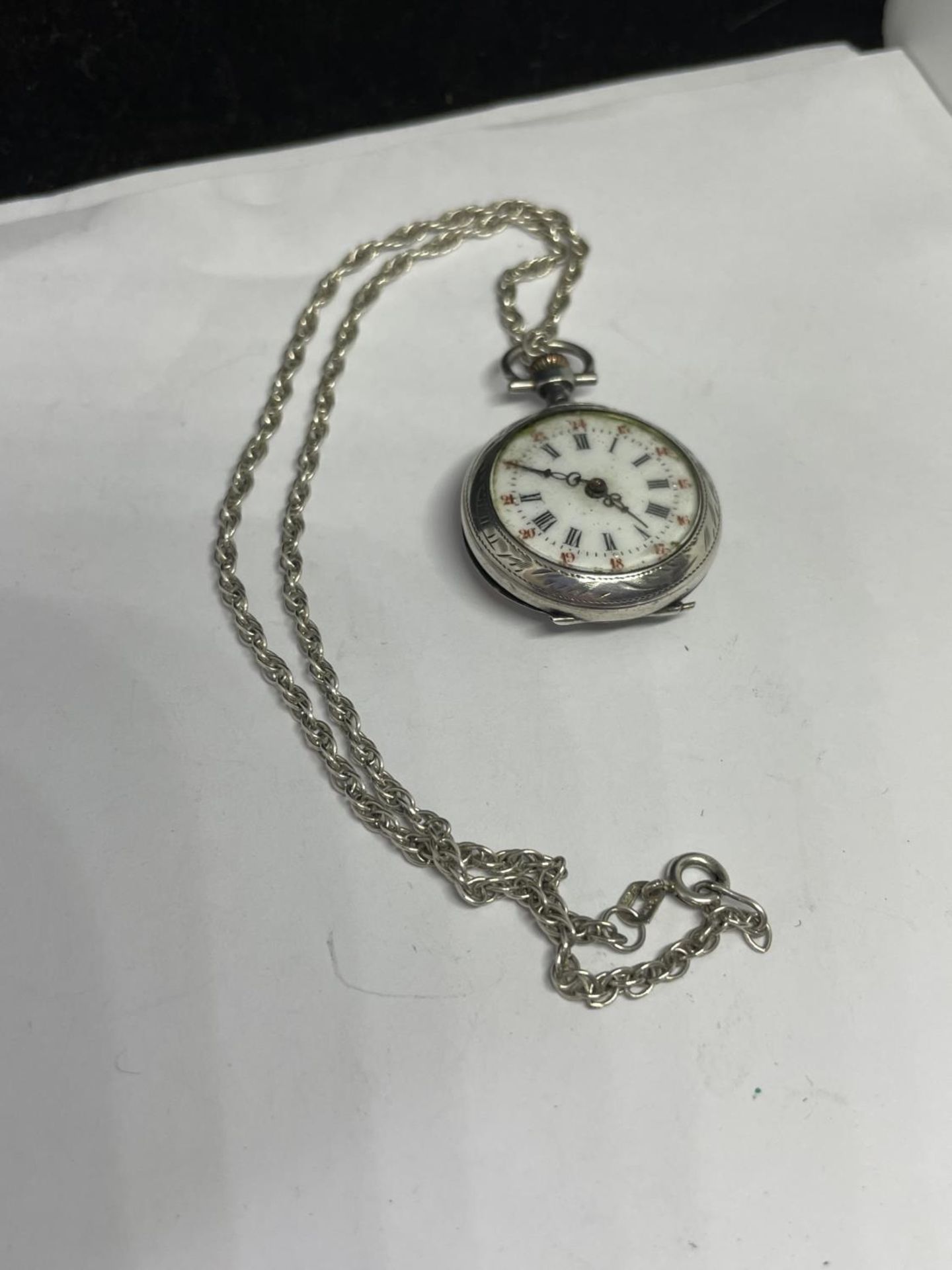 A DECORATIVE FOB WATCH ON A MARKED SILVER CHAIN