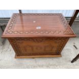 A MODERN HARDWOOD BLANKET CHEST WITH CARVING TO TOP AND FRONT, COMPLETE WITH METALWARE CARRYING