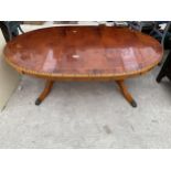 AN OVAL YEW WOOD AND CROSSBANDED COFFEE TABLE WITH TIGER PRINT TYPE DECORATION TO THE RIM, ON TWIN