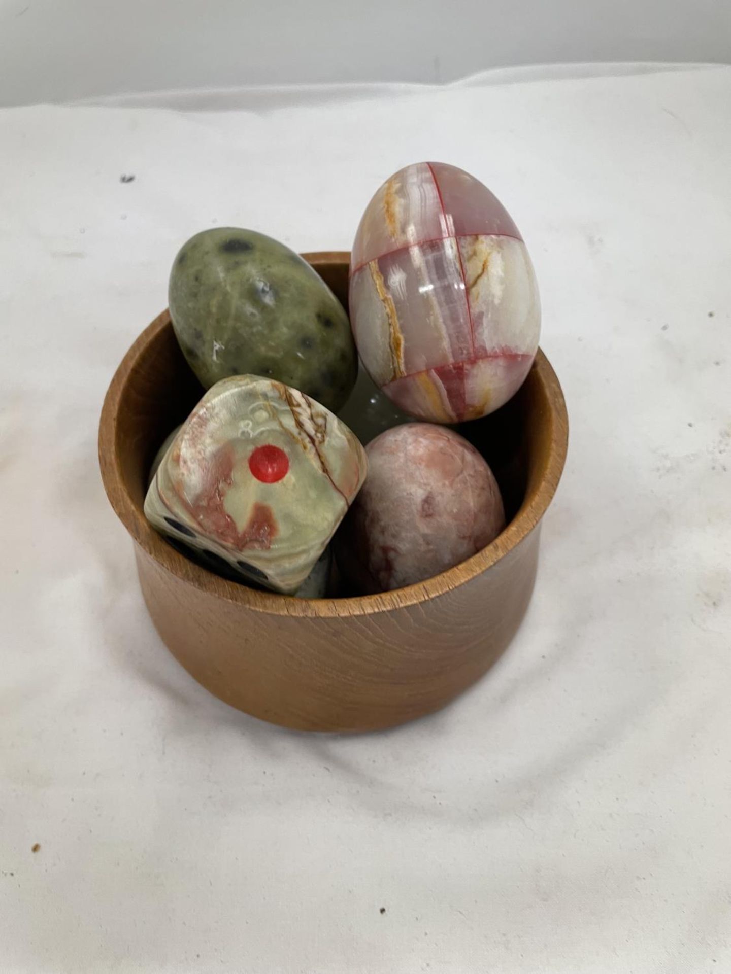 A WOODEN POT CONTAINING FIVE ONYX EGGS AND AN ONYX DICE