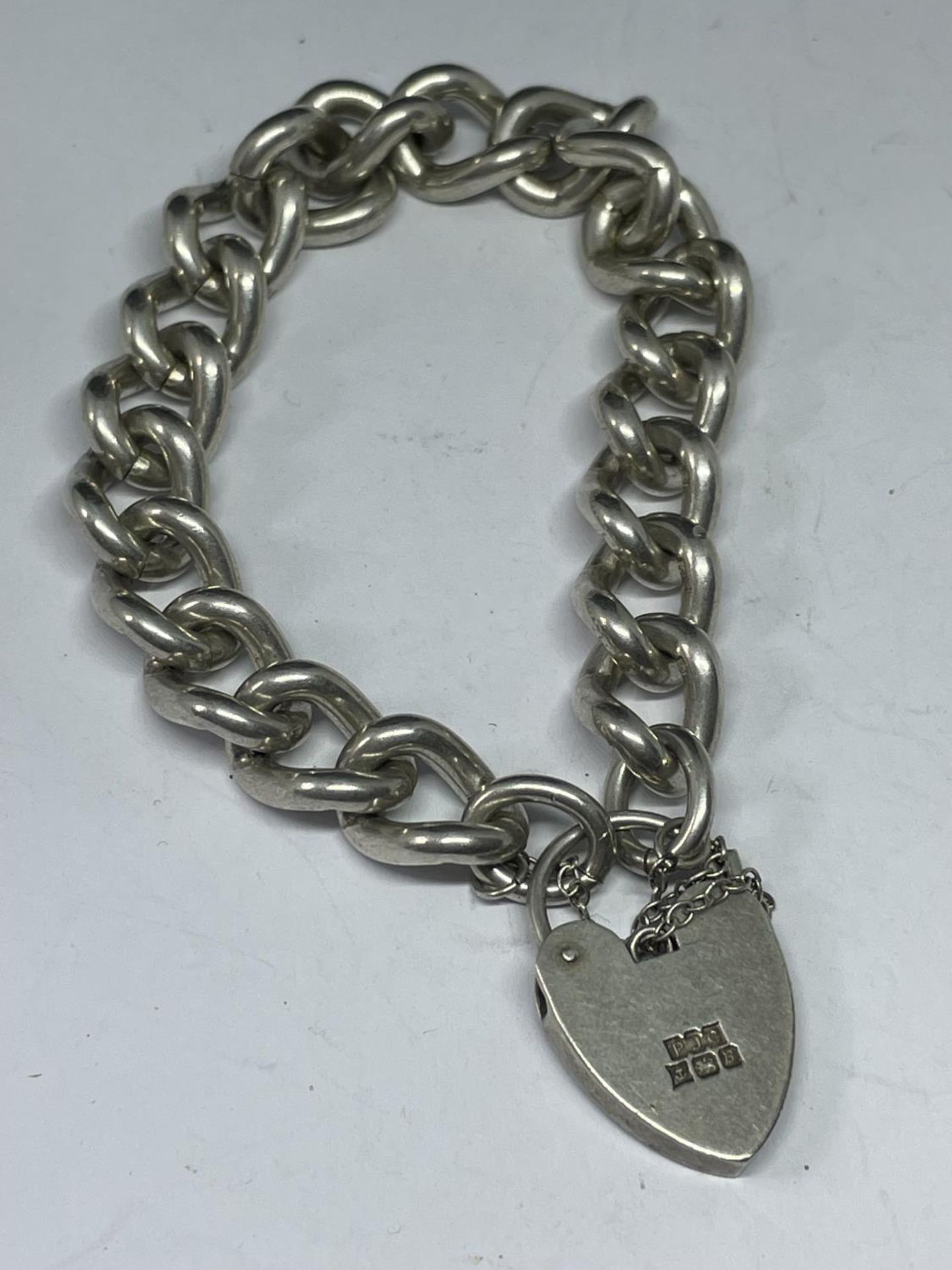 A HEAVY MARKED SILVER BRACELET WITH HALLMARKED BIRMINGHAM SILVER HEART LOCJ