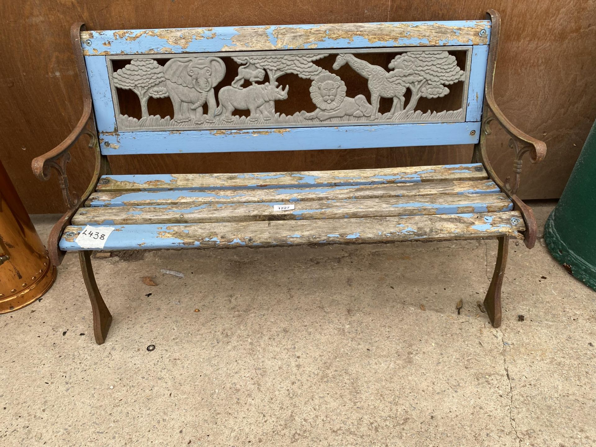 A SMALL WOODEN SLATTED CHILDRENS BENCH WITH CAST ENDS AND PLASTIC SAFARI BACK