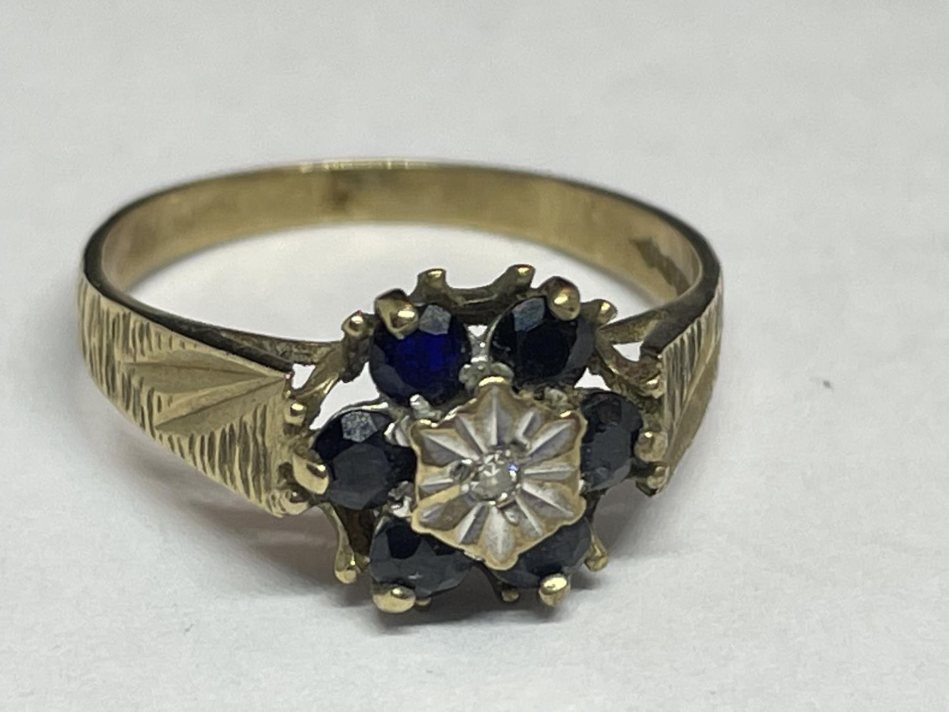 A 9 CARAT GOLD RING WITH A CENTRE DIAMOND SURROUNDED BY SAPPHIRES SIZE N/M