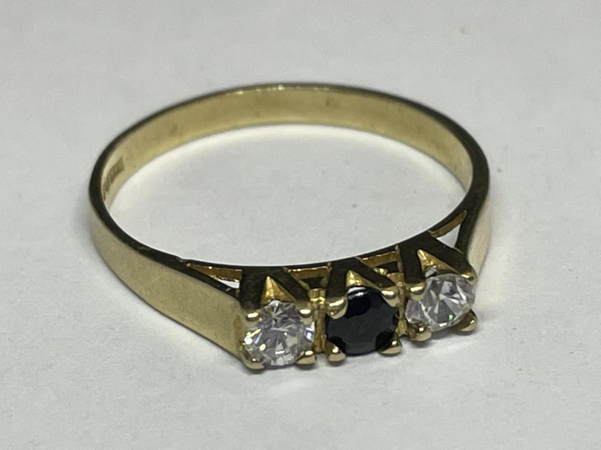 A 9 CARAT GOLD RING WITH THREE IN LINE STONES TO INCLUDE A CENTRE SAPPHIRE AND TWO CUBIC ZIRCONIAS