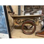 A WOODEN AND METAL VINTAGE CART WITH A HANDPAINTED FLORAL DESIGN COULD BE USED AS A GARDEN PLANTER