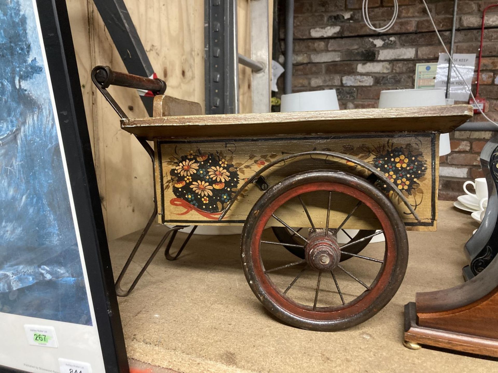 A WOODEN AND METAL VINTAGE CART WITH A HANDPAINTED FLORAL DESIGN COULD BE USED AS A GARDEN PLANTER