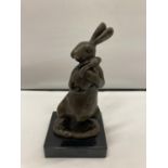 A SIGNED BRONZE RABBIT HOLDING HER BABY ON A MARBLE BASE