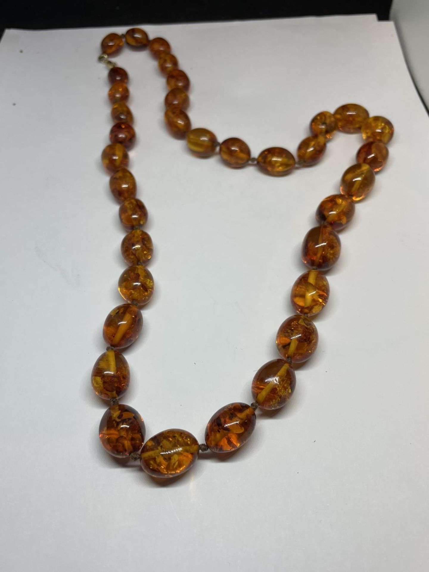 A KNOTTED AMBER NECKLACE WITH A MARKED 9K CLASP