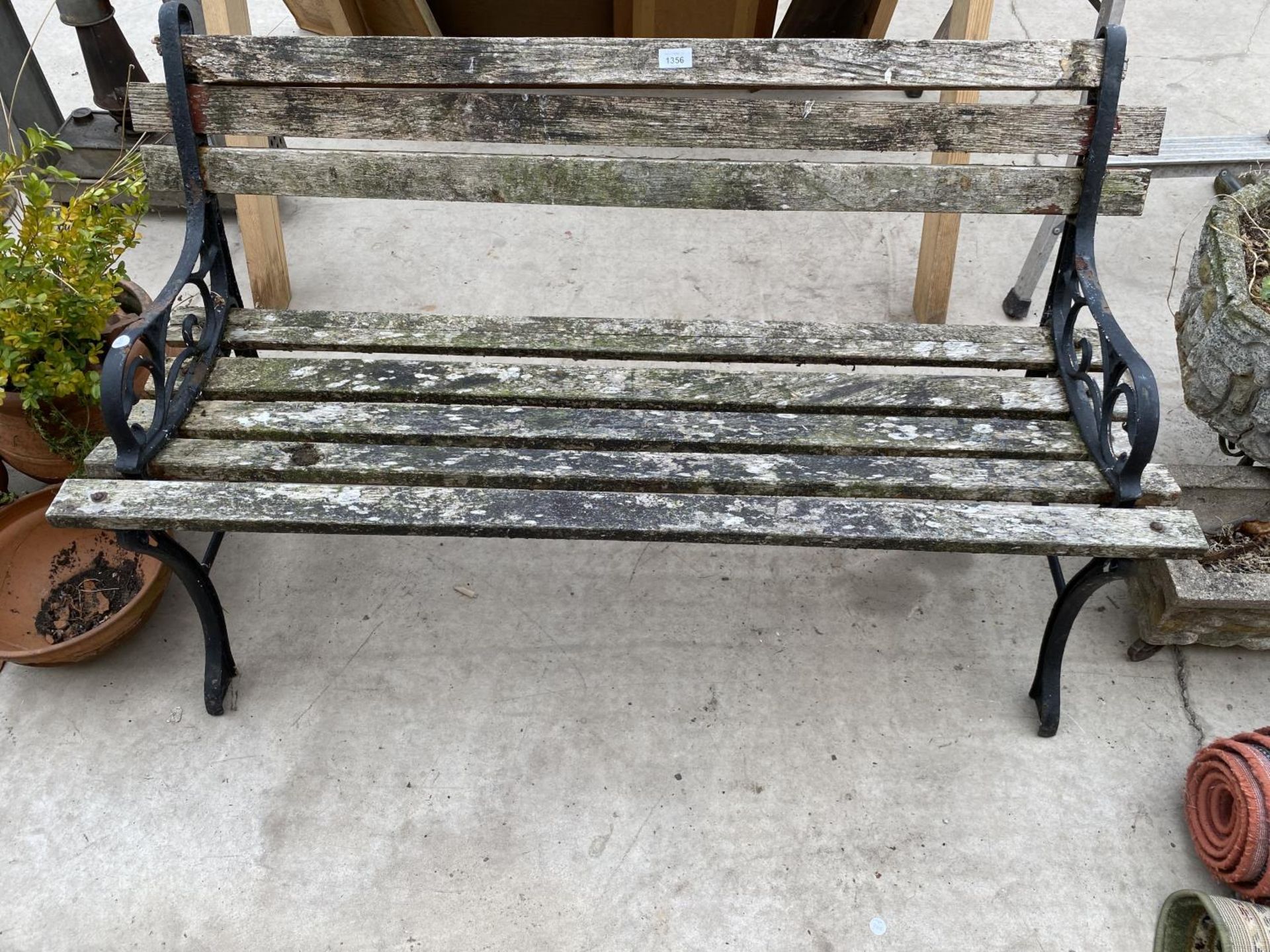 A WOODEN SLATTED GARDEN BENCH WITH CAST BENCH ENDS