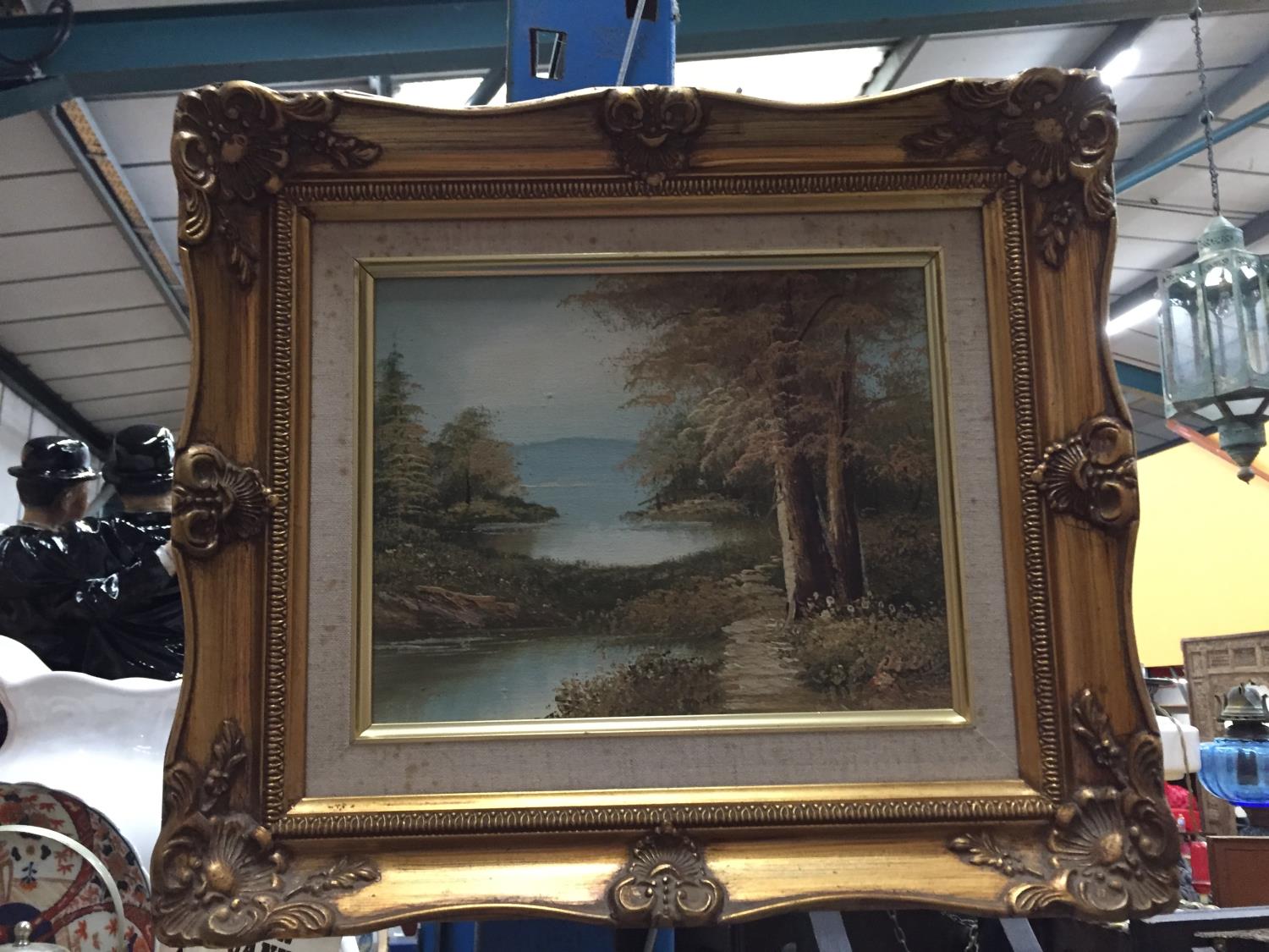 A GILT FRAMED OIL ON CANVAS OF A LAKE SCENE SET IN FORESTRY SIGNED DARBY W: 39CM