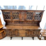 A REPRODUCTION OAK WEBBER FURNITURE DRESSER WITH CARVED DOORS AND GLAZED AND LEADED UPPER PORTION,