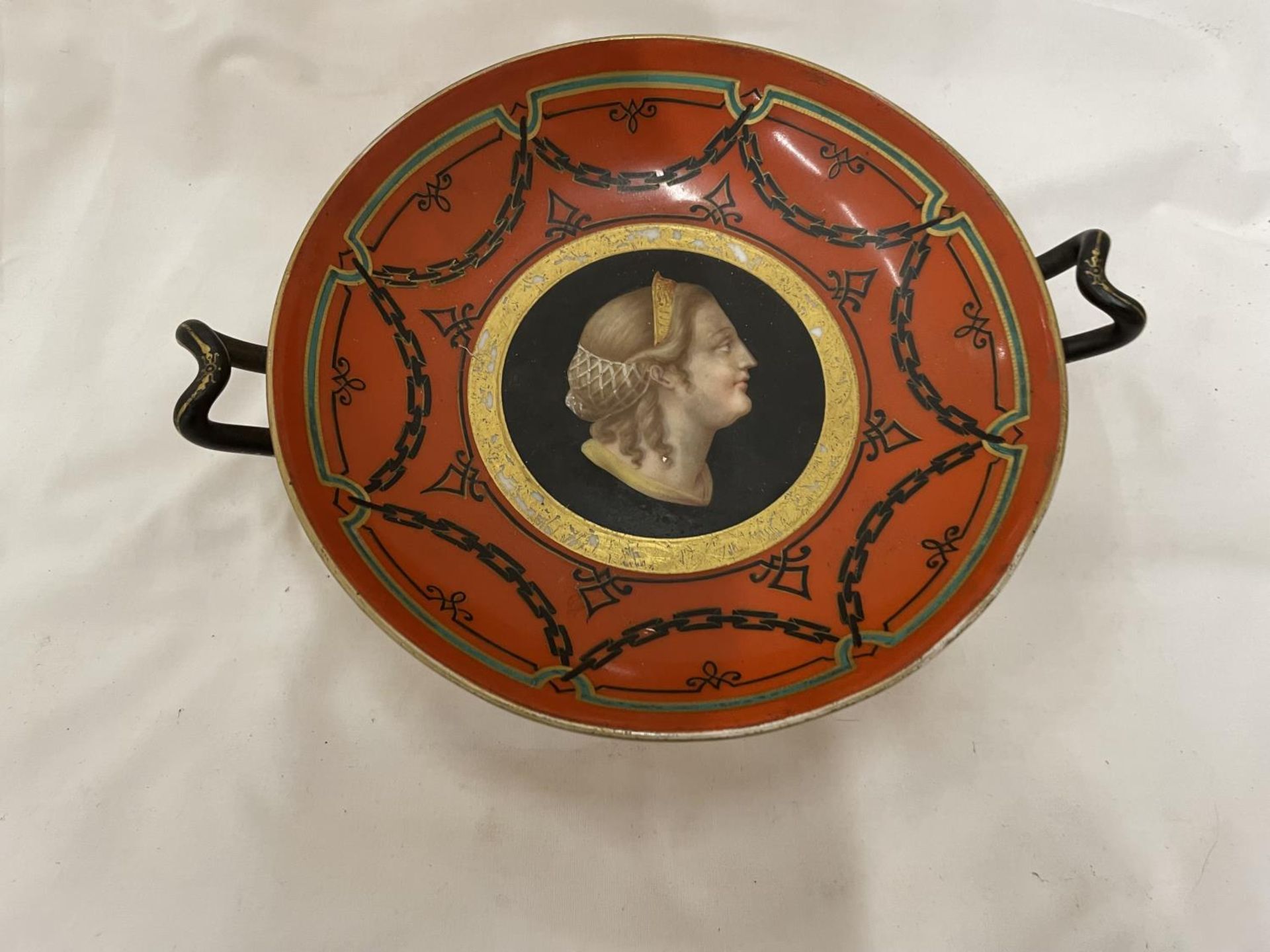 A VICTORIAN HANDLED 'TAZZA' DECORATED IN RED WITH A LADY'S PORTRAIT IN THE MIDDLE HEIGHT 9CM,