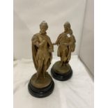 A PAIR OF GOLD COLOURED METAL FIGURES ON PLINTHS, WITH HOLES TO THE TOP - POSSIBLY LAMP BASES HEIGHT