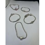 FIVE MARKED SILVER BRACELETS TO INCLUDE A CHAMILLIA WITH FOUR CHARMS AND A PANDORA WITH SAFETY CHAIN