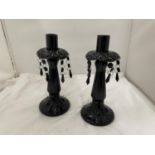 A PAIR OF BLACK GLASS CANDLESTICKS WITH CRYSTAL STYLE DROPLETS, HEIGHT 25.5CM