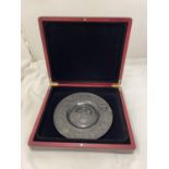 A VINTAGE PEWTER PLATE WITH EMBOSSED SCENES OF MEDIEVAL STYLE HORSEMEN, DIAMETER 19.5CM, BOXED - A/F