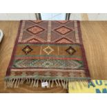 A SMALL RED AND GREEN PATTERNED FRINGED RUG