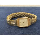 AN 18CT GOLD CASED LADIES WATCH ON A ROLLED GOLD BRACELET