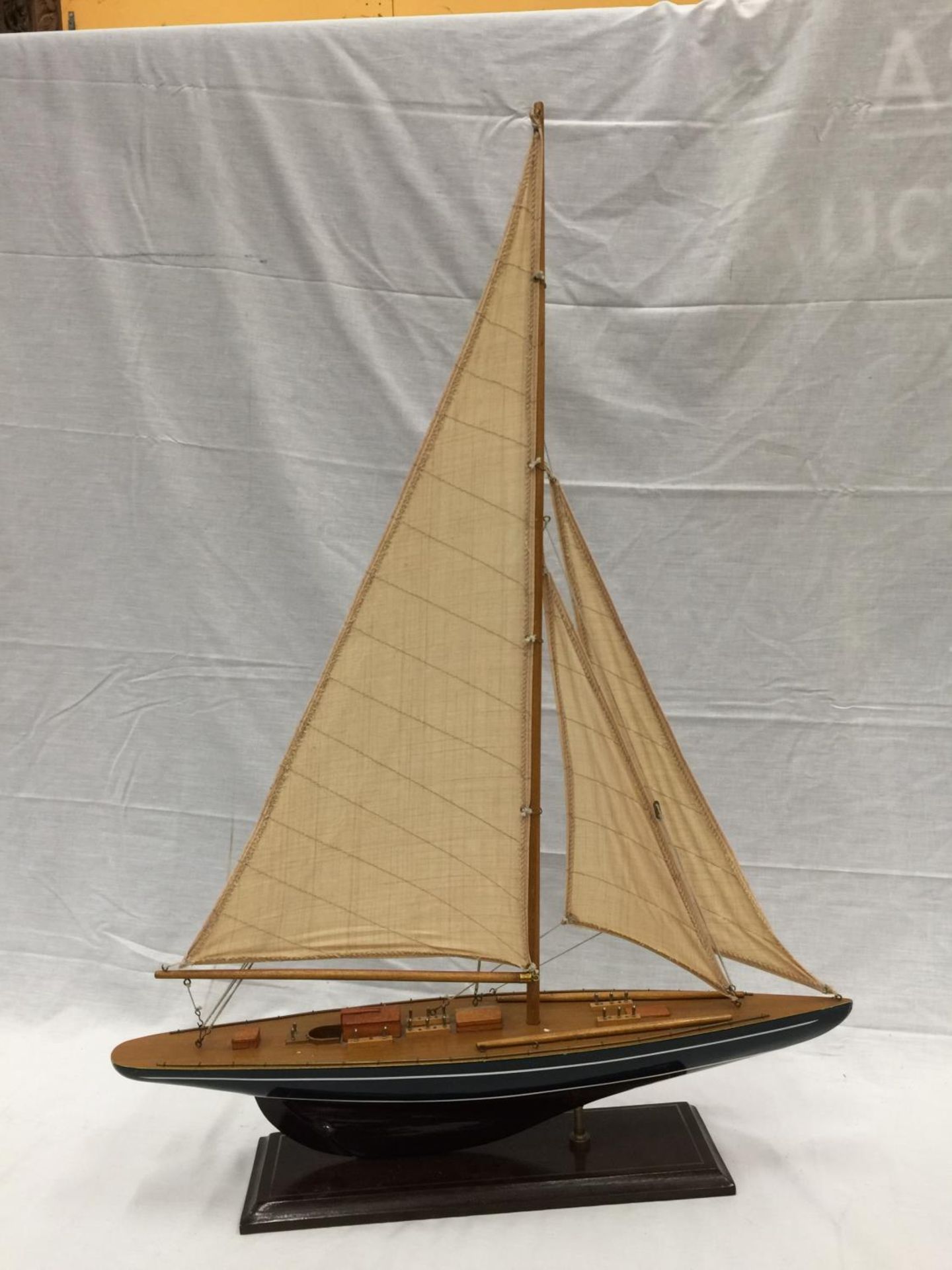 A MODEL OF A HAND PAINTED SINGLE MASTED SAILING SHIP ON A STAND L: 61CM