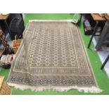 A LARGE FRINGED RUG IN BEIGE, PALE GREEN AND NAVY