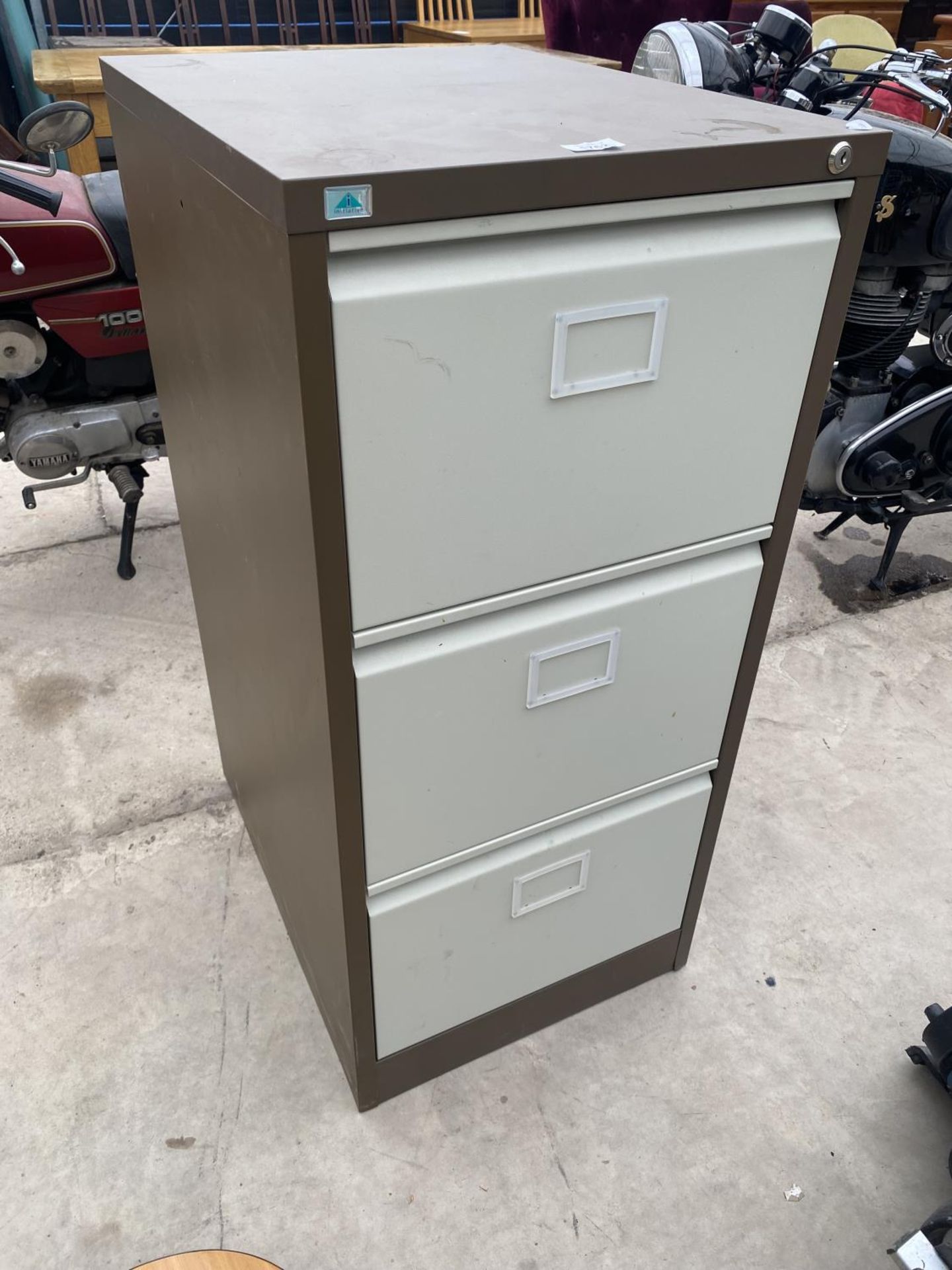A BROWN AND CREAM THREE DRAWER METAL FILING CABINET