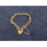 A HALLMARKED SILVER BRACELET WITH A HALLMARKED HEART SHAPED LOCK ON A CURB LINK BRACELET