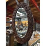 A MAHOGANY FRAMED OVAL MIRROR WITH BEVELLED GLASS, HAND CARVED IN MACCLESFIELD 71CM X 50CM