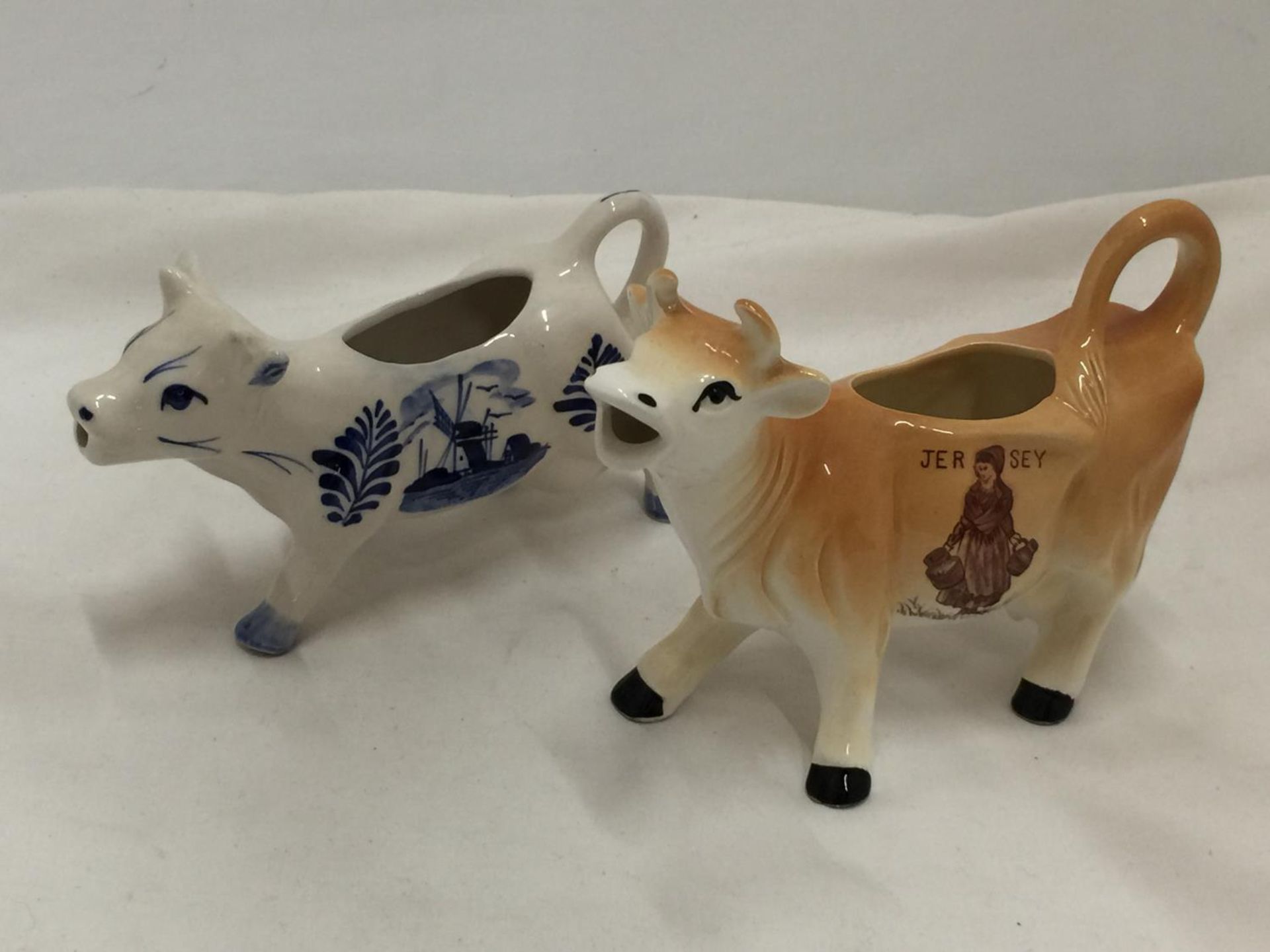A DELFT BLUE HANDPAINTED COW CREAMER AND A JERSEY COW CREAMER