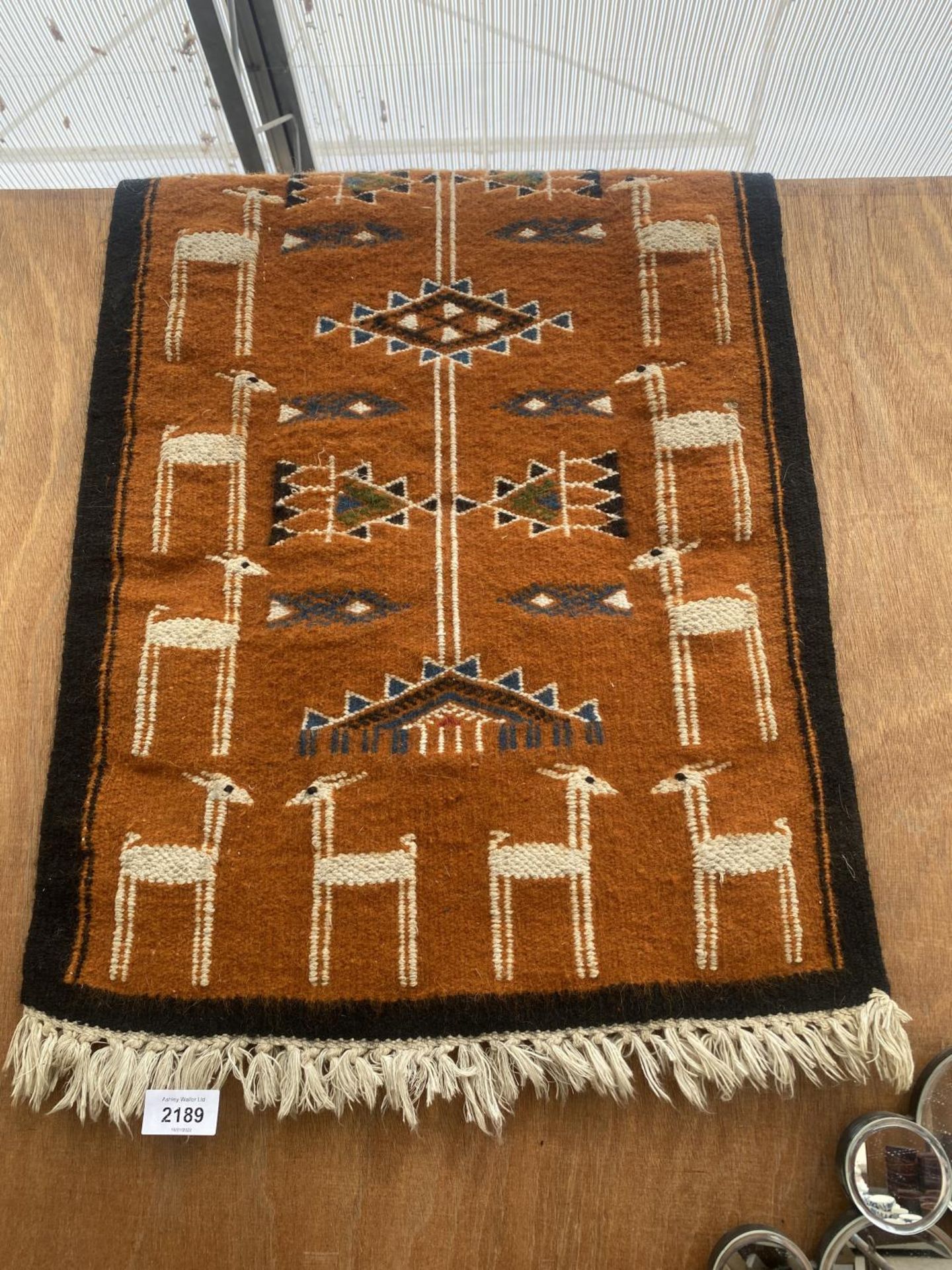 A SMALL HANDMADE PERUVIAN RUG WITH LLAMA PATTERN