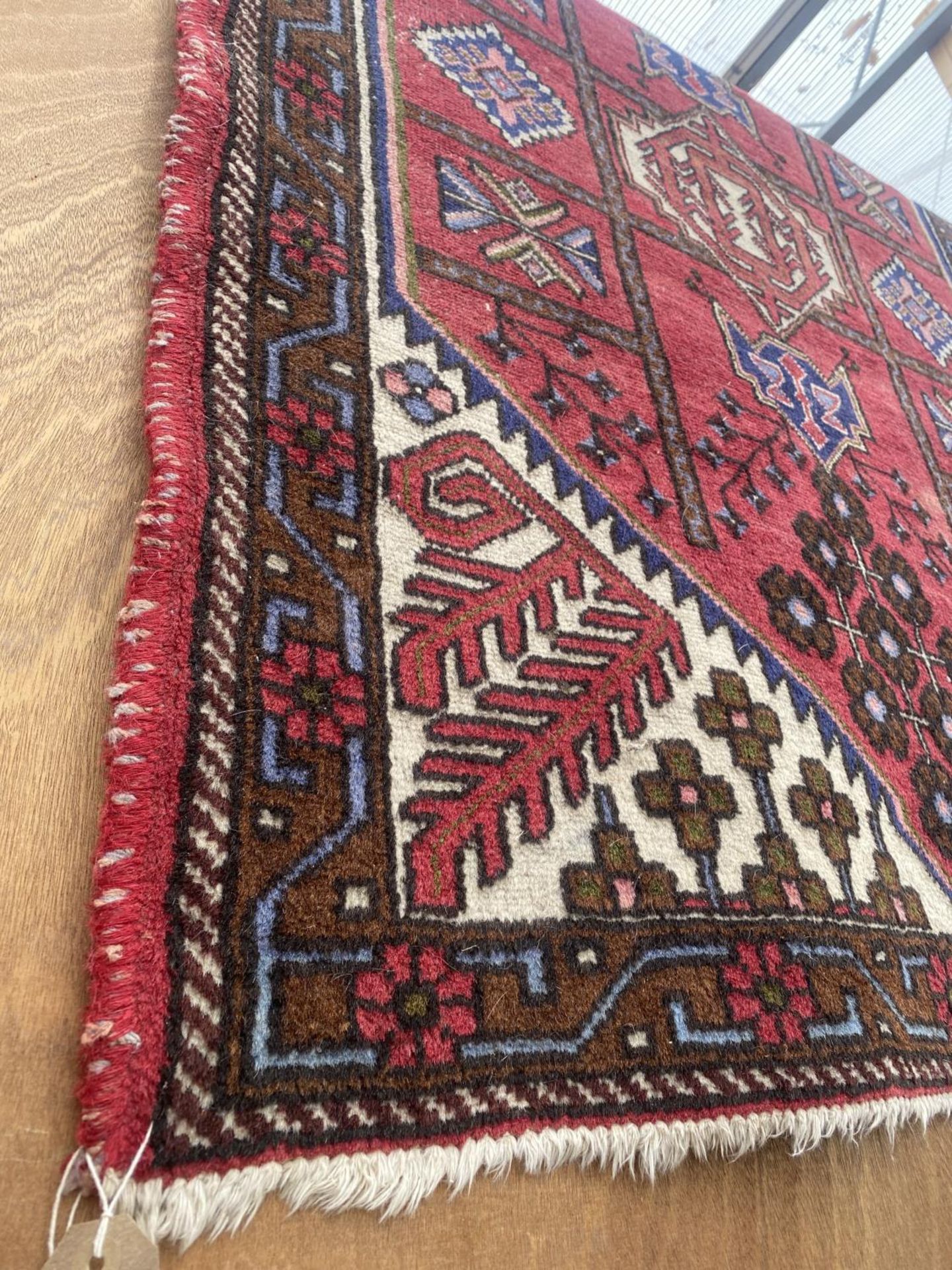 A LARGE RED PATTERNED FRINGED RUG - Image 2 of 2