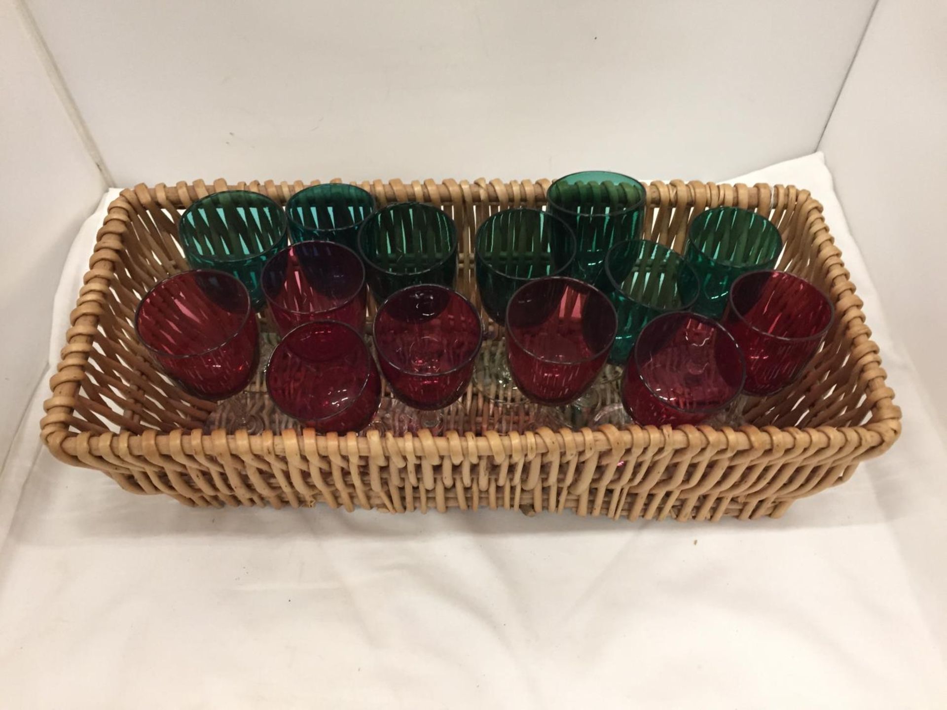 A WICKER BASKET CONTAINING FOURTEEN RED AND GREEN WINE GLASSES