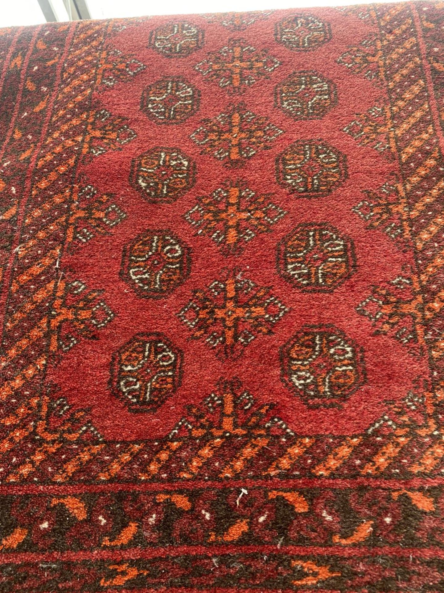 A RED PATTERNED FRINGED RUG - Image 3 of 3