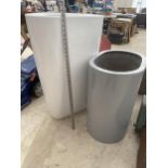 A LARGE WHITE TRIANGULAR FIBRE GLASS PLANTER AND A FURTHER GREY FIBRE GLASS PLANTER