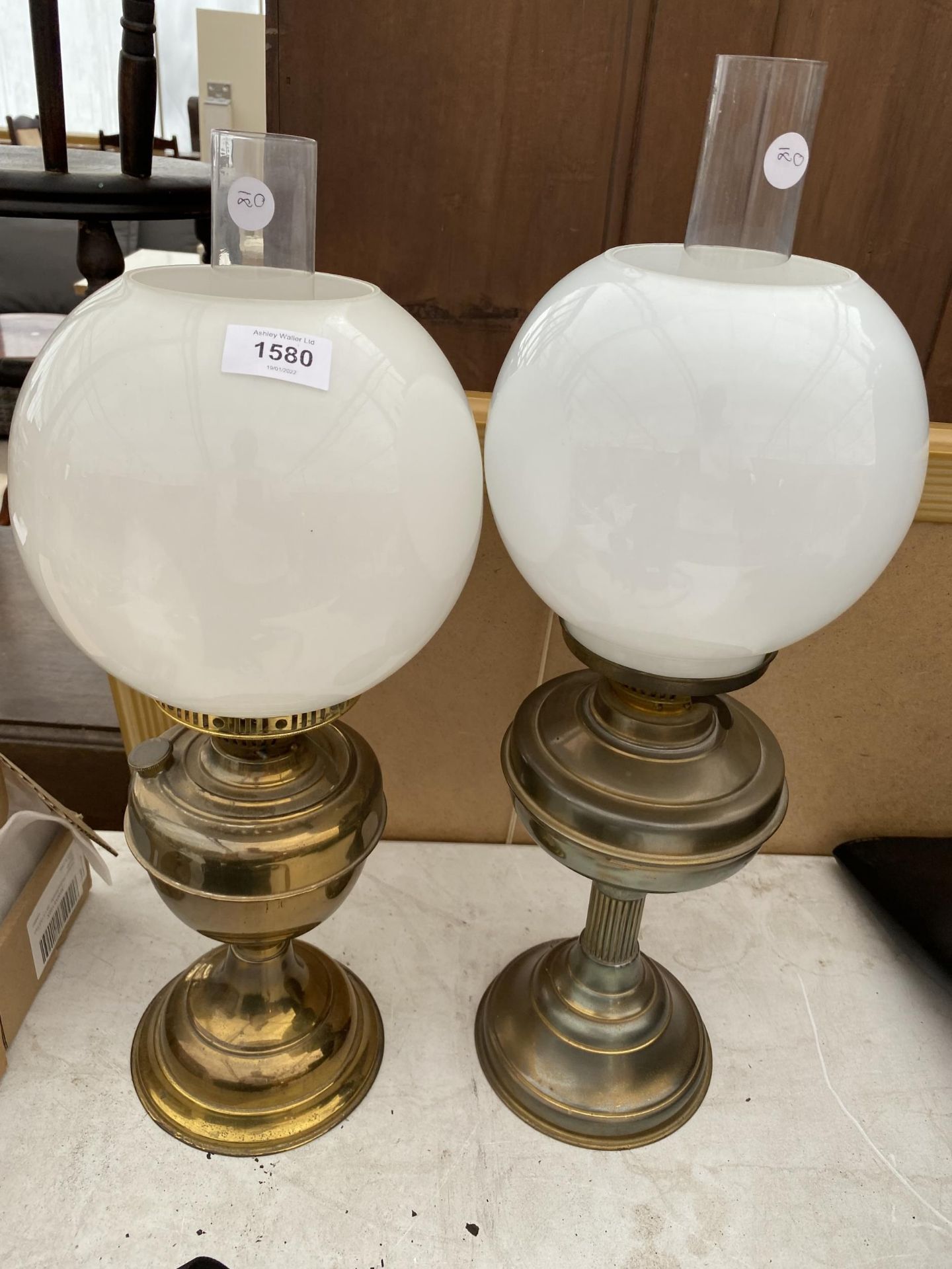A NEAR PAIR OF BRASS OIL LAMPS WITH GLASS SHADES
