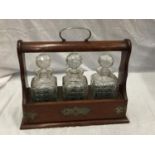 A MAHOGANY TANTALUS WITH BRASS DETAILING AND THREE CUT GLASS DECANTERS. COMES WITH KEY BUT WILL