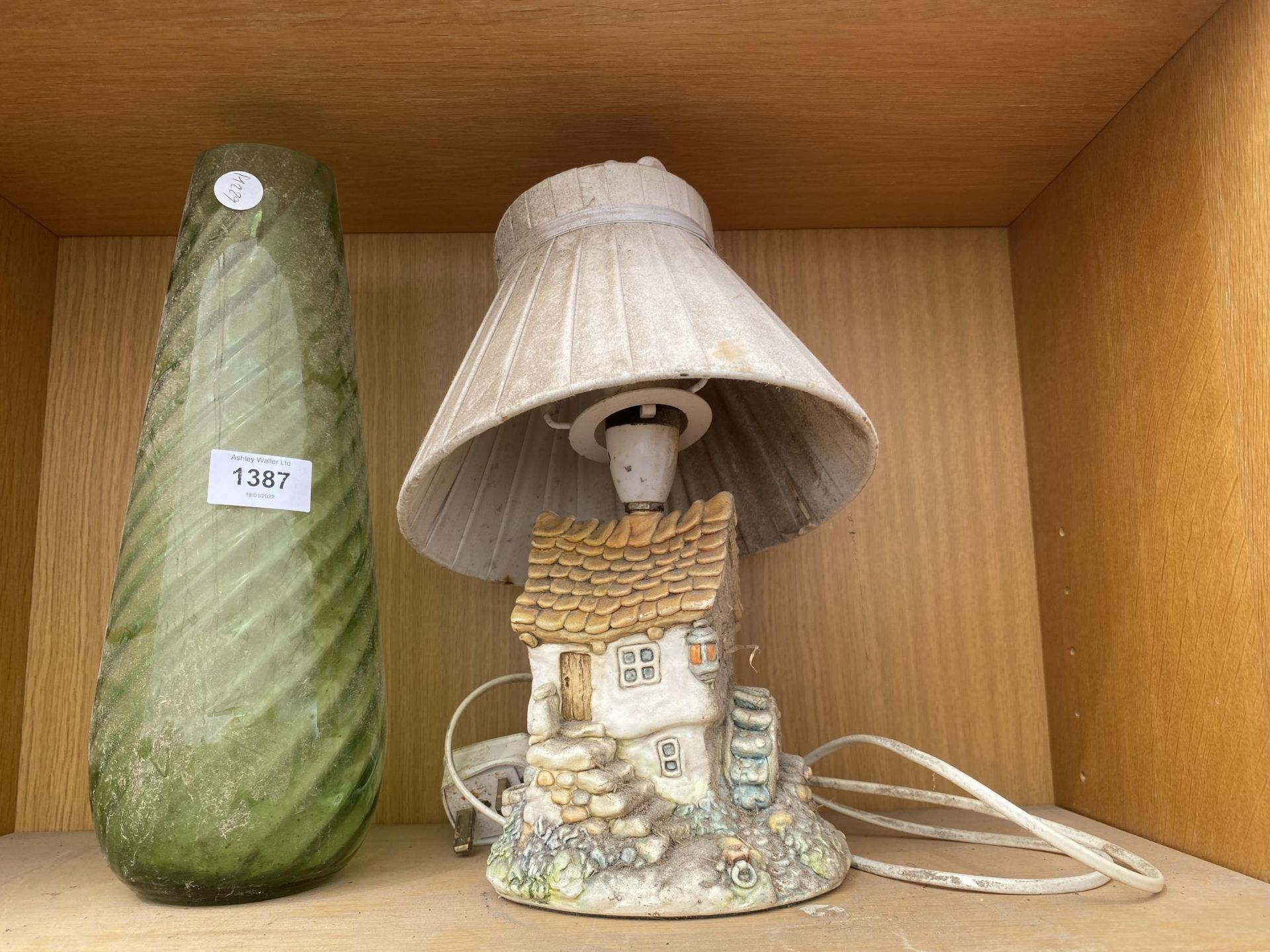 A GREEN GLASS VASE AND A COTTAGE TABLE LAMP