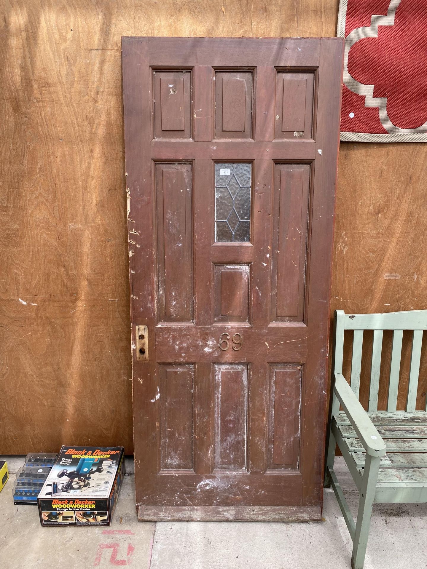 A WOODEN HOUSE DOOR WITH LEADED WINDOW AND NUMBERED 69