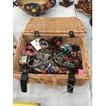 A WICKER BASKET CONTAINING A QUANTITY OF COSTUME JEWELLERY TO INCLUDE BANGLES, BRACELETS, NECKLACES,