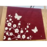 A MODERN RED AND FLORAL PATTERNED RUG