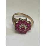 A 9 CARAT GOLD RING WITH RED AND CLEAR STONES IN A FLOWER DESIGN SIZE L/M WITH A PRESENTATION BOX
